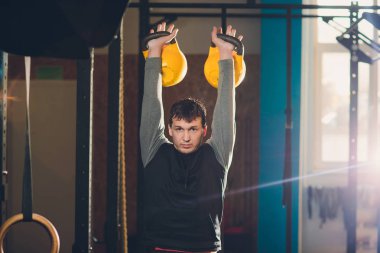 Genç adam kaldırma dumbbell ve kettlebell fitness Center.