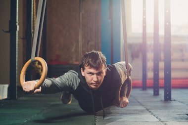 Jimnastik jimnastik halkaları üzerinde yoğun egzersiz yapan kas-up egzersiz atletik erkek.