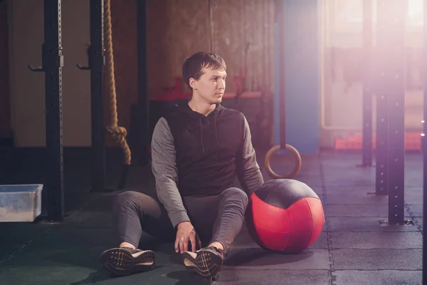 Lekkoatletycznego mężczyzna robi brzuch ćwiczenia na podłodze. Człowiek robi treningu za pomocą piłką na siłowni. — Zdjęcie stockowe