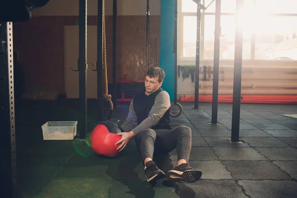 Lekkoatletycznego mężczyzna robi brzuch ćwiczenia na podłodze. Człowiek robi treningu za pomocą piłką na siłowni. — Zdjęcie stockowe