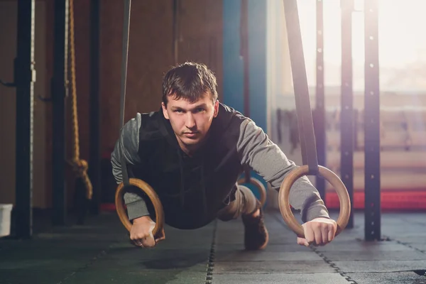 Мышечные упражнения спортсмен делает интенсивную тренировку в тренажерном зале на гимнастических кольцах . — стоковое фото