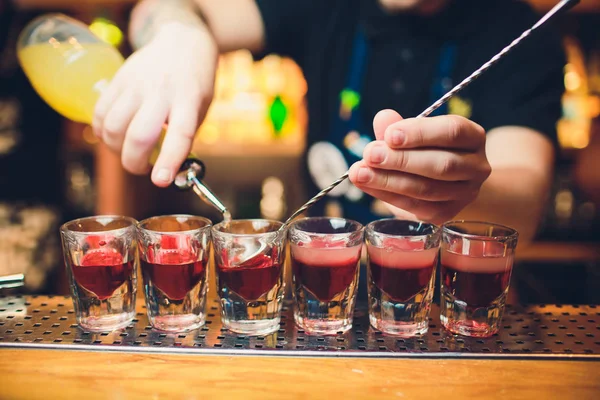 Barkeeper gießt Tequila ins Glas vor dem Hintergrund der Bar. — Stockfoto