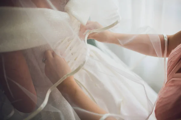 Vacker, blond brud i vit lyxklänning gör sig redo för bröllop. Morgonförberedelser. Kvinna ta på klänning. — Stockfoto