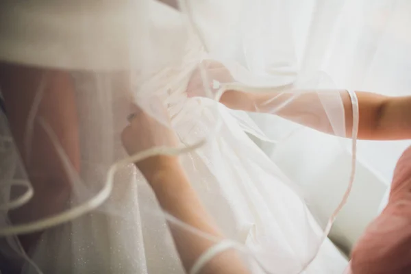 Linda, noiva loira em vestido de luxo branco está se preparando para o casamento. Preparativos matinais. Mulher vestindo vestido . — Fotografia de Stock