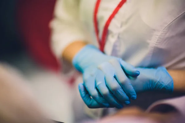 Primer plano de las manos de las médicas poniéndose guantes quirúrgicos esterilizados azules en el consultorio. —  Fotos de Stock