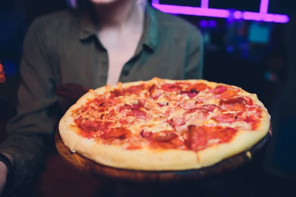Pizza mit Fleisch, Käse und Gemüse in den Händen des Kellners. Servieren Sie Ihre Gerichte — Stockfoto