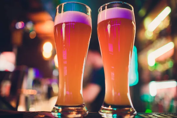 Bir bar masasında iki bardak bira. Arka planda bira musluğu. — Stok fotoğraf