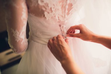 Beyaz lüks elbiseli, güzel, sarışın gelin düğüne hazırlanıyor. Sabah hazırlıkları. Giyinen kadın.