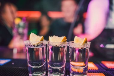 Aperatif barında arkadaşlarınızla, beş bardak alkol aperatifler kireç ve antep fıstığı, tuz ve biber ile dekorasyon için biber. Tekila, votka, viski, ROM. seçici odak ve kopya alanı.