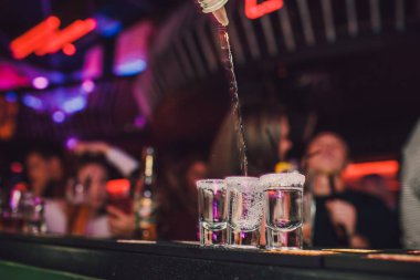Aperatif barında arkadaşlarınızla, beş bardak alkol aperatifler kireç ve antep fıstığı, tuz ve biber ile dekorasyon için biber. Tekila, votka, viski, ROM. seçici odak ve kopya alanı.