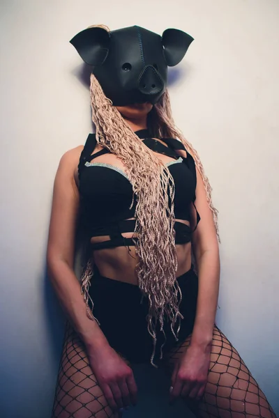 Varkens mascotte kostuum dans striptease vrouw in zwart leer varken masker. — Stockfoto