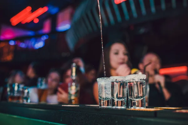 Aperatif barında arkadaşlarınızla, beş bardak alkol aperatifler kireç ve antep fıstığı, tuz ve biber ile dekorasyon için biber. Tekila, votka, viski, ROM. seçici odak ve kopya alanı.