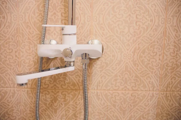 В ванной комнате, открытый душ смеситель прикреплен к настенной кронштейн, тонированное черно-белое изображение, вертикальный формат . — стоковое фото