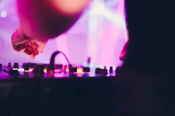 DJ playing music at mixer on colorful blurred background. — Stock Photo, Image