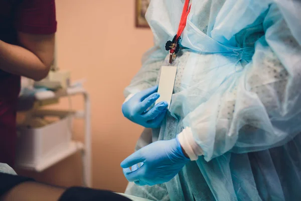 Primo piano delle mani dei medici femminili che indossano guanti chirurgici sterilizzati blu in ufficio. — Foto Stock