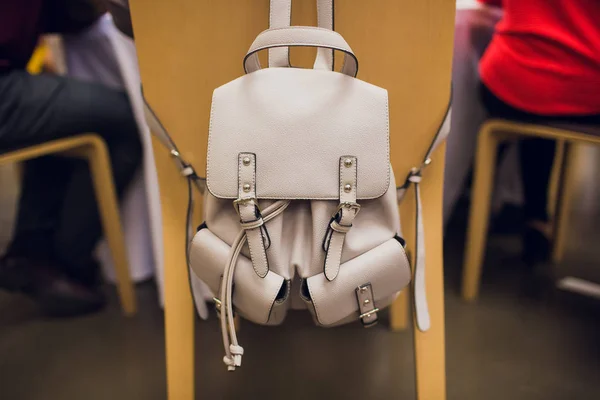 Bolso beige colgado en una silla negra sobre fondo gris . — Foto de Stock