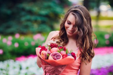 Buket çiçek ve elinde kaba kağıt sarılı taze narenciye