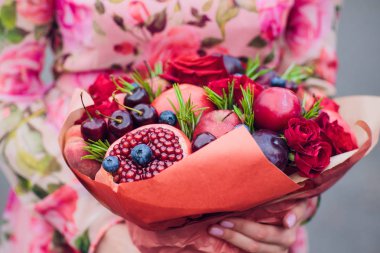 Buket çiçek ve elinde kaba kağıt sarılı taze narenciye