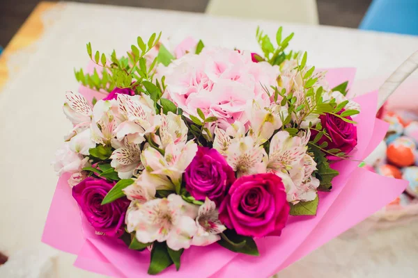 Blumenschmuck, Party, Ehekonzept. es gibt einen kleinen, aber feinen Blumenstrauß, der aus Rosen in verschiedenen Farben und Pfingstrosen besteht, die mit Blättern verziert sind. — Stockfoto