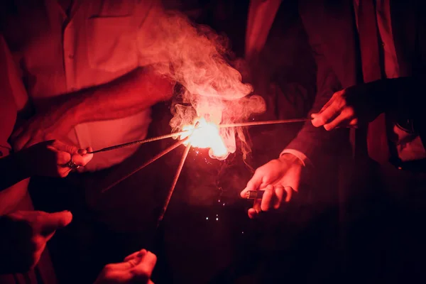 Rekreační zázemí s prskavky. Mladí přátelé drží Bengálsko světla, closeup, selektivní fokus. Oslava svátků narozenin nebo v zimě — Stock fotografie