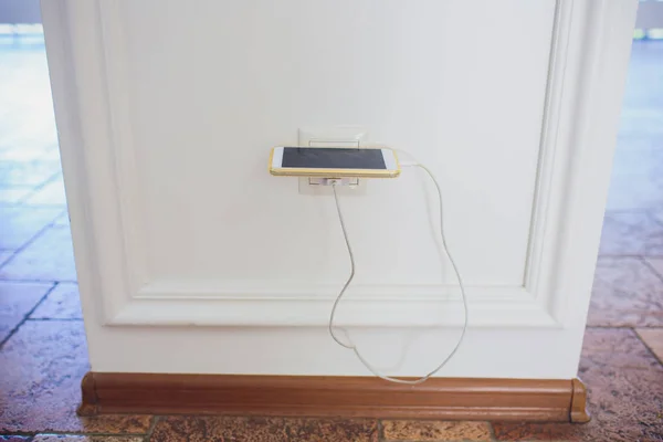 Carga de baterías en un teléfono inteligente con enchufe y pared. Vertical . — Foto de Stock