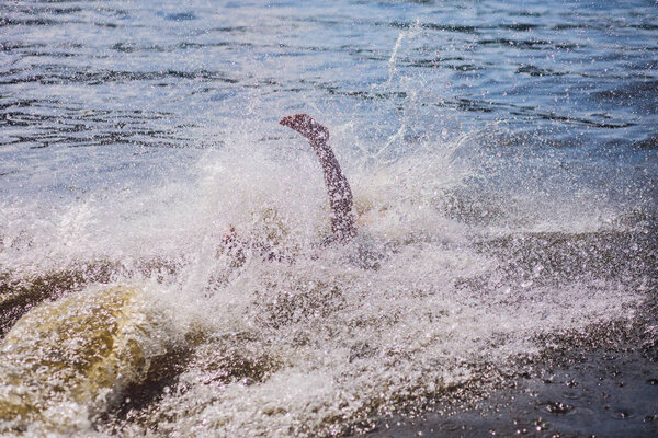 Молодой человек прыгает в воду
