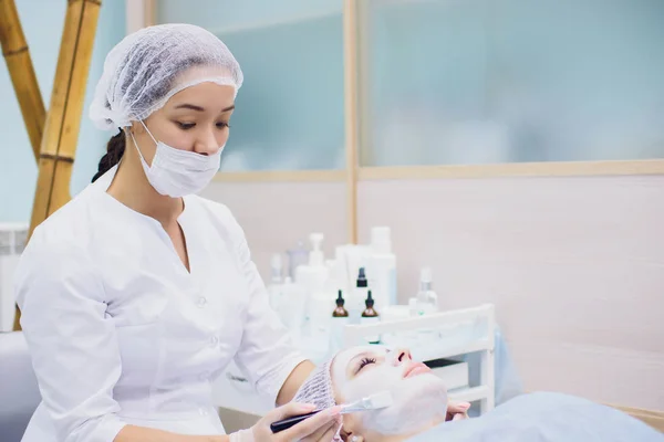 Medicul-cosmetolog face o procedură de curățare facială cu ultrasunete a pielii unei femei frumoase, tinere în salonul de înfrumusețare, spa. Cosmetologie și îngrijire profesională a pielii . — Fotografie, imagine de stoc
