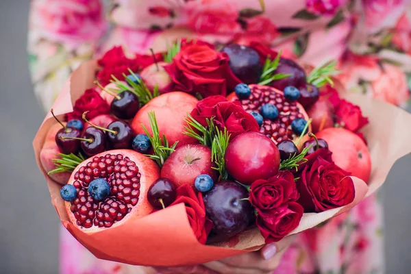 Bukiet kwiatów i świeżych owoców cytrusowych, owinięte w grubej księdze w ręce — Zdjęcie stockowe