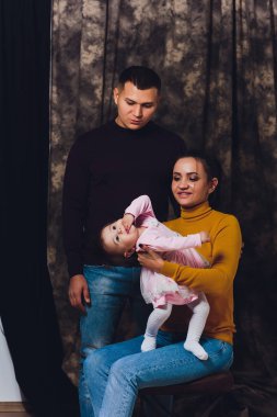 Mutlu aile portresi. Perents çocuklarının evde tutan gülümseyerek. Yakışıklı baba ve küçük tatlı kızım faving eğlenceli güzel annem.