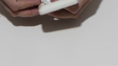 Hand cleaning a white home kitchen flat panel light switch with a white cotton cloth dust rag as part of regular housecleaning chores.