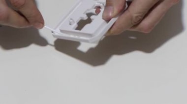 Hand cleaning a white home kitchen flat panel light switch with a white cotton cloth dust rag as part of regular housecleaning chores.