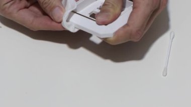 Hand cleaning a white home kitchen flat panel light switch with a white cotton cloth dust rag as part of regular housecleaning chores.