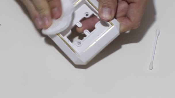 Hand cleaning a white home kitchen flat panel light switch with a white cotton cloth dust rag as part of regular housecleaning chores. — Stok video
