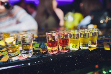 Bar tezgahında servis edilen sert alkollü içkilerin çeşitleri. Arka planda bulanık şişeler.