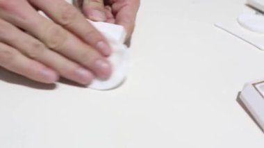 Hand cleaning a white home kitchen flat panel light switch with a white cotton cloth dust rag as part of regular housecleaning chores.