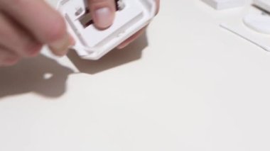 Hand cleaning a white home kitchen flat panel light switch with a white cotton cloth dust rag as part of regular housecleaning chores.