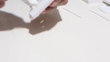 Hand cleaning a white home kitchen flat panel light switch with a white cotton cloth dust rag as part of regular housecleaning chores.