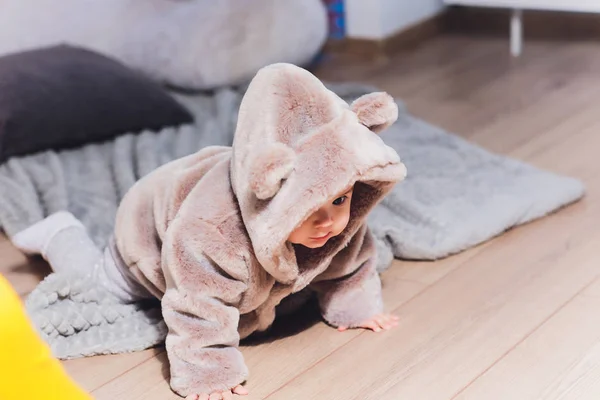Λίγο χαριτωμένο μωρό σε ένα κοστούμι με αρκούδες στο πάτωμα. — Φωτογραφία Αρχείου