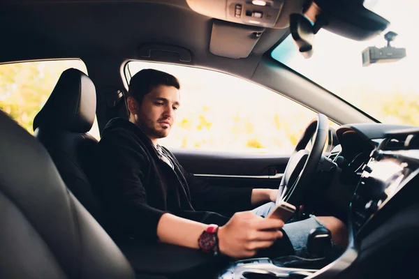 Tiro de un hombre guapo usando el teléfono móvil mientras conduce . —  Fotos de Stock