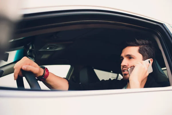 Tiro de un hombre guapo usando el teléfono móvil mientras conduce . — Foto de Stock