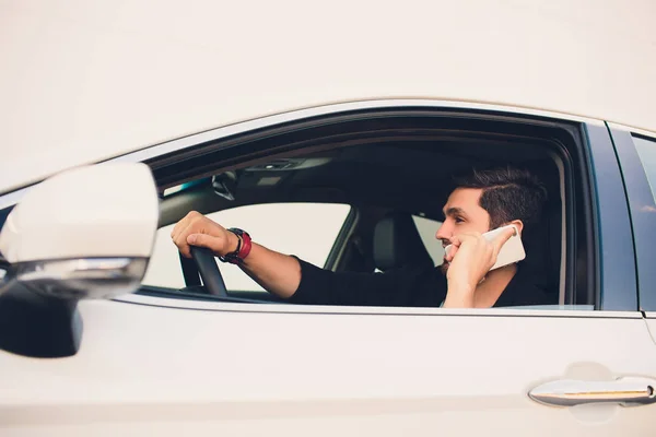 Tiro de un hombre guapo usando el teléfono móvil mientras conduce . — Foto de Stock