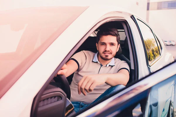 Retrato joven hombre guapo sonriendo en su propio coche — Foto de Stock