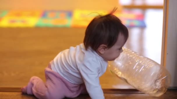 Dítě holčičku sedí s lahví pitné vody v plenky a dát pět otevřenou rukou znamení úsměvu. — Stock video