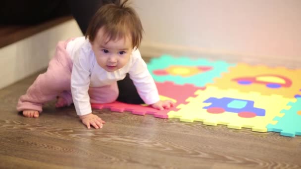 Vue latérale d'une mignonne petite fille se trouve et tient tapis de jeu puzzle coloré avec des chiffres à la maison . — Video