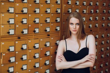 siyah düz saçlı güzel genç kız kutusu ve veri arar Kitaplığı'nda dosya dolabı açar