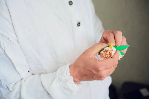 En brudar hand sätta boutonniere blomman på brudgummen — Stockfoto