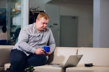 Office çalışma kavramı. Adam ofiste rahat beyaz koltukta oturan onun laptop tarama