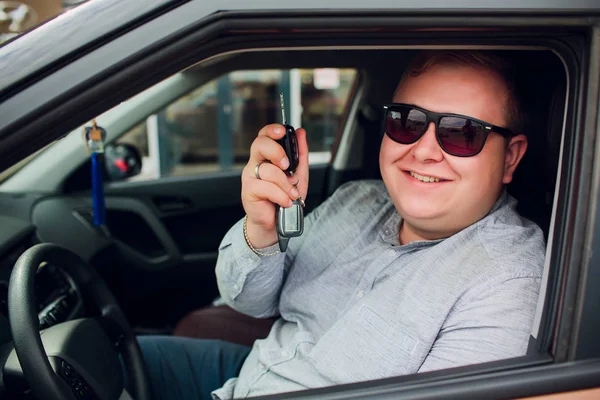 Nadšený podnikatel sedí v autě ukazuje nový klíč od auta — Stock fotografie