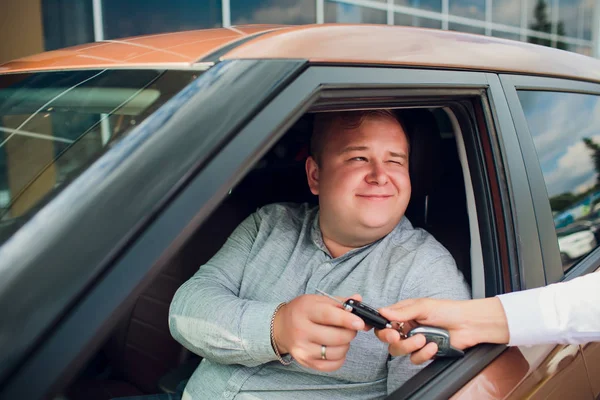 Nadšený podnikatel sedí v autě ukazuje nový klíč od auta — Stock fotografie
