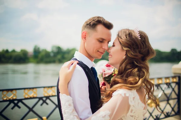 Elegante novia y novio posando en el fondo del río . —  Fotos de Stock